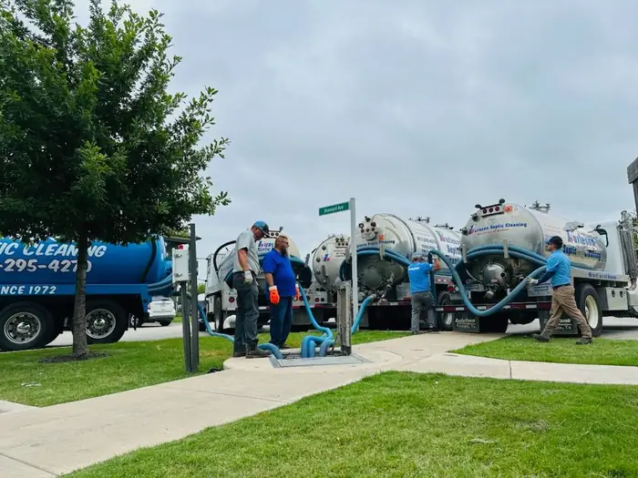 A Burleson Septic crew running hose from the truck to the tank on site